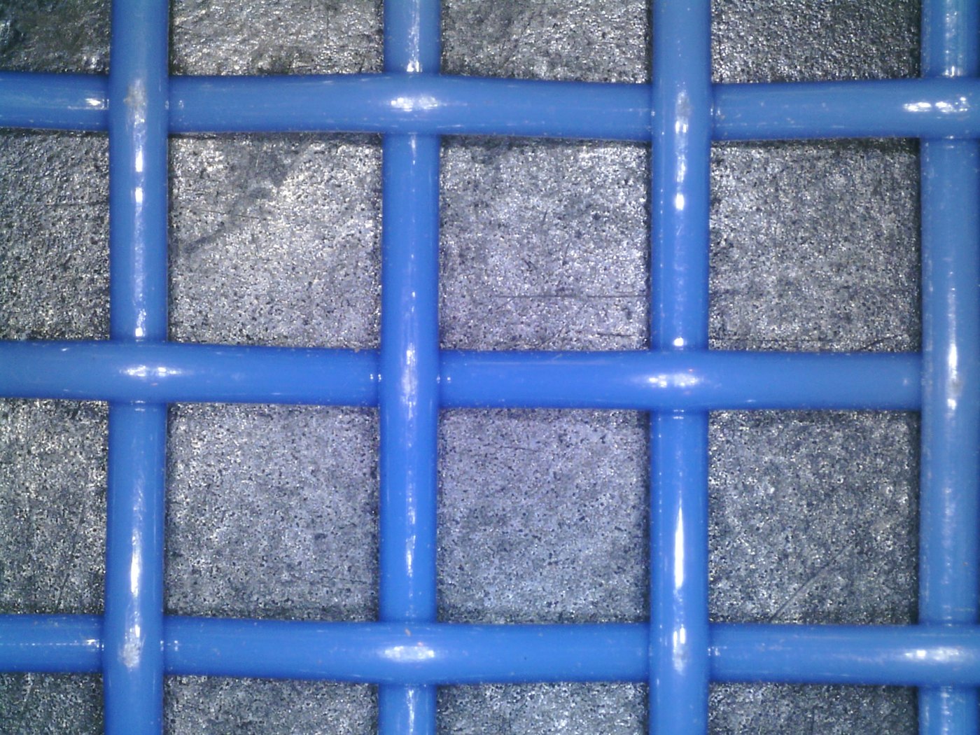 Electron-microscope close-up of a blue square mesh belt showing uniform woven openings